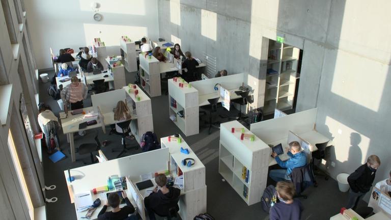  "plan b: Zwischen Wald und WLAN-Revolution im Klassenzimmer": Schüler arbeiten in einem  großen Klassenraum mit separierten Arbeitsinseln.