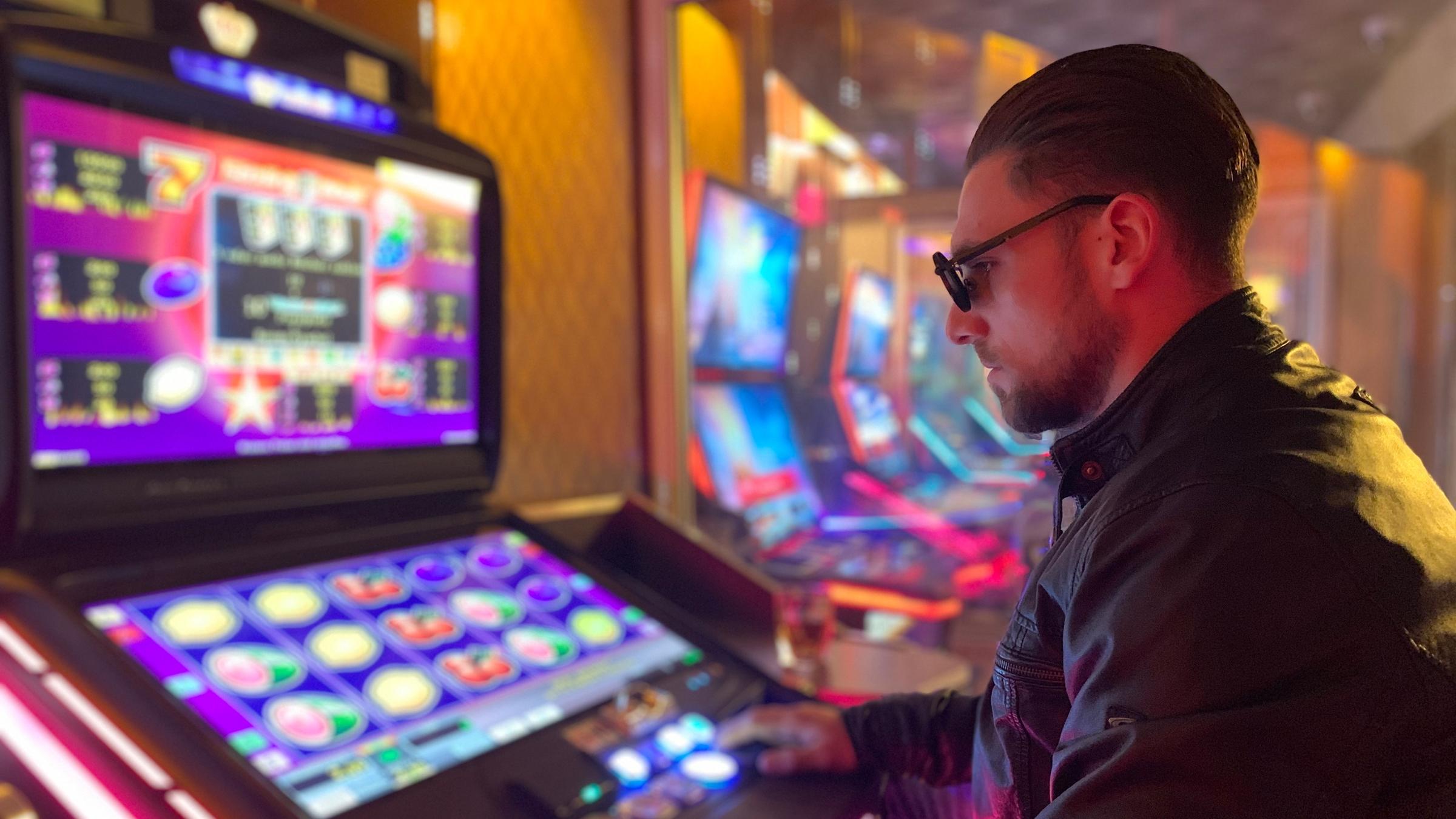 "37°: Verzockt - Wenn Glückspiel zur Sucht wird": Junger Mann sitzt in einer Spielhölle vor einem Spielautomaten und spielt.