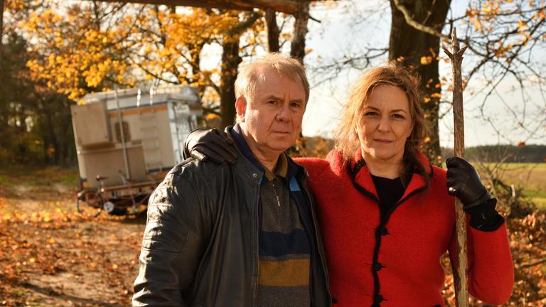 "Endlich Witwer - Forever Young": Georg Weiser (Joachim Król,l) und Petra (Martina Gedeck,r.) stehen in Abstand vor dem liegengebliebenen Wohnmobil eng nebeneinander und schauen skeptisch  voraus.