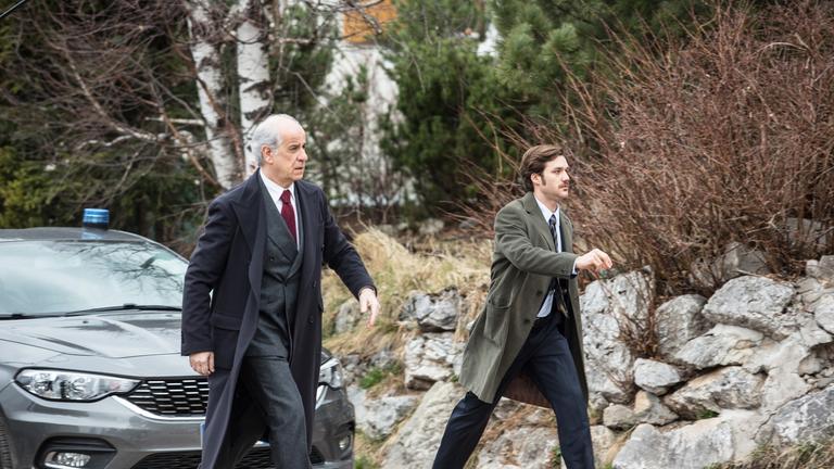 "Der Nebelmann": Sonderermittler Vogel (Toni Servillo) und sein Assistent Borghi (Lorenzo Richelmy) laufen einen Weg entlang. Hinter ihnen steht ein Wagen.