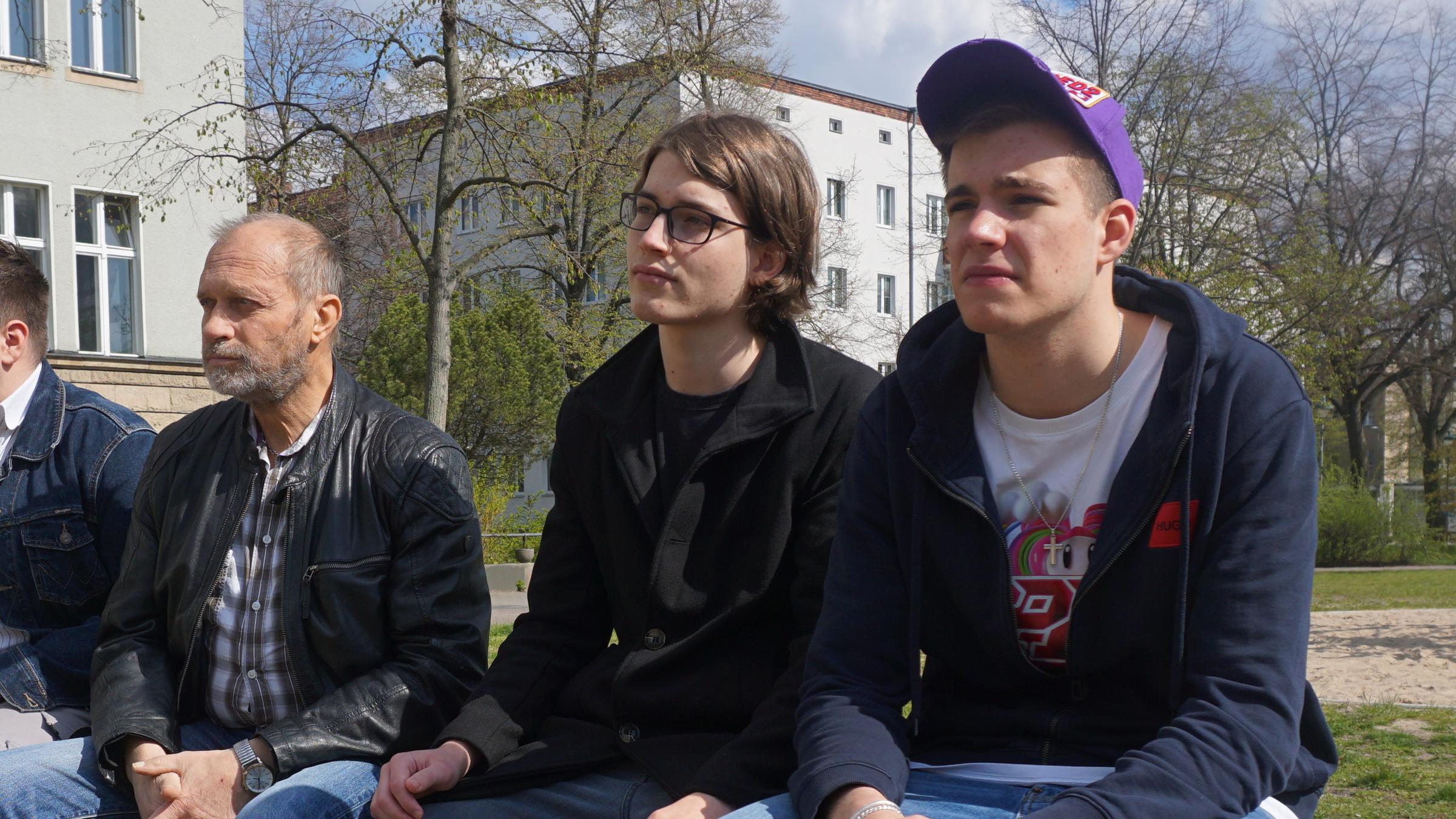"ZDFzoom: Am Ende arm?": Gerald sitzt mit zwei jungen Männern auf einer Parkbank. Alle drei schauen in die gleiche Richtung.