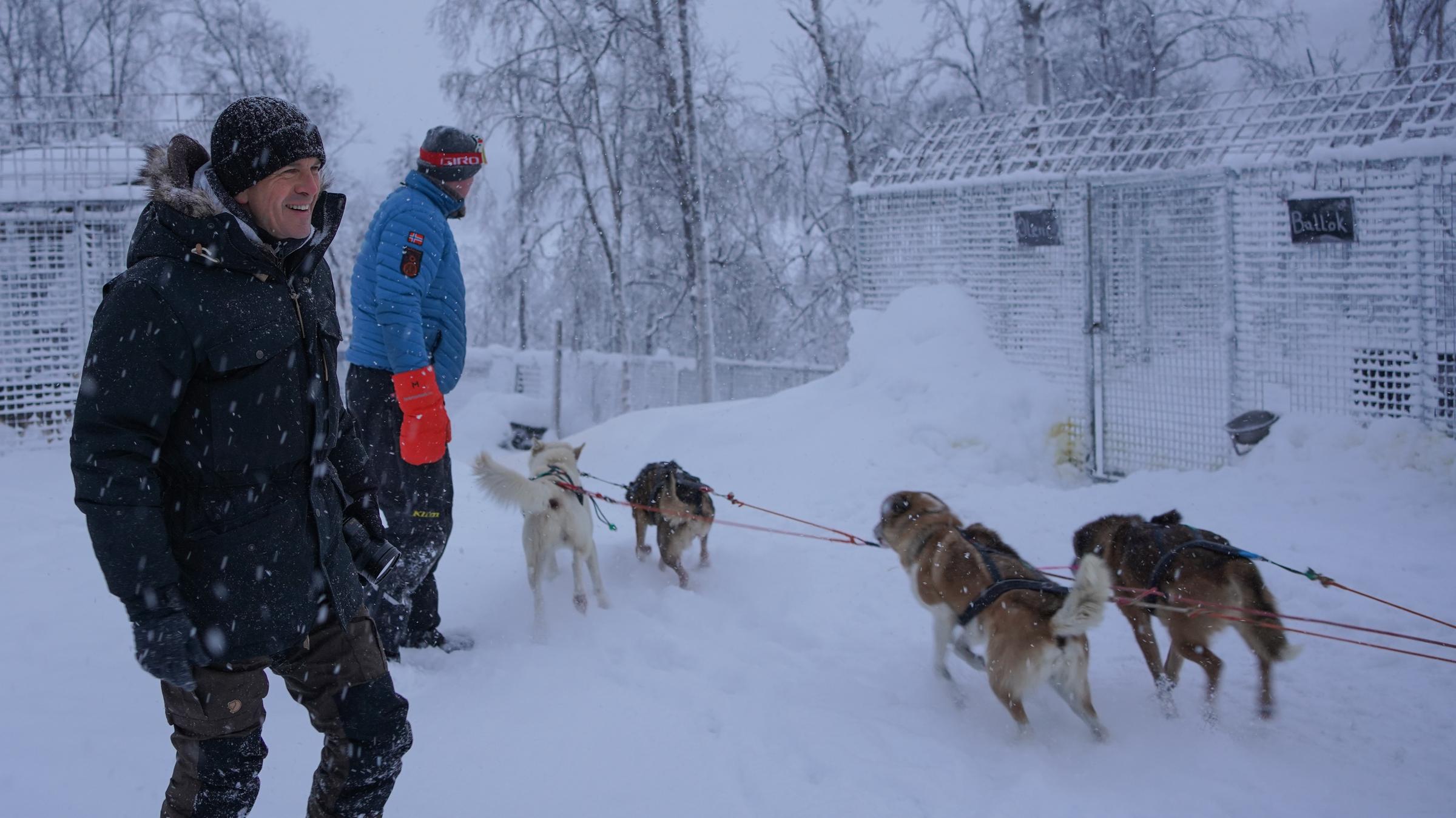 "Markus Lanz - Schweden ungeschminkt": Moderator Markus Lanz steht mit einem Musher und seinen Schlittenhunden im verschneiten Wald.