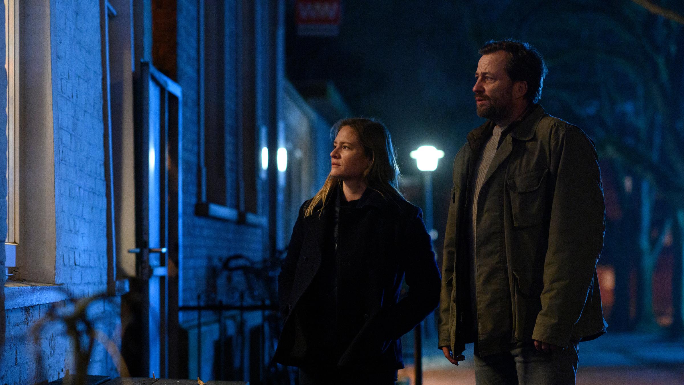 "Ostfriesenangst": Ann Kathrin Klaasen (Julia Jentsch) und Frank Weller (Christian Erdmann) stehen in der Dunkelheit auf der Straße und schauen durch ein Fenster.