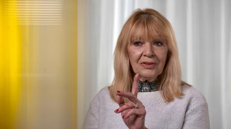 "Ku'damm 63 - Die Dokumentation": Nahaufnahme von Cindy Berger in einem rosa Pullover mit erhobenem Zeigefinger.