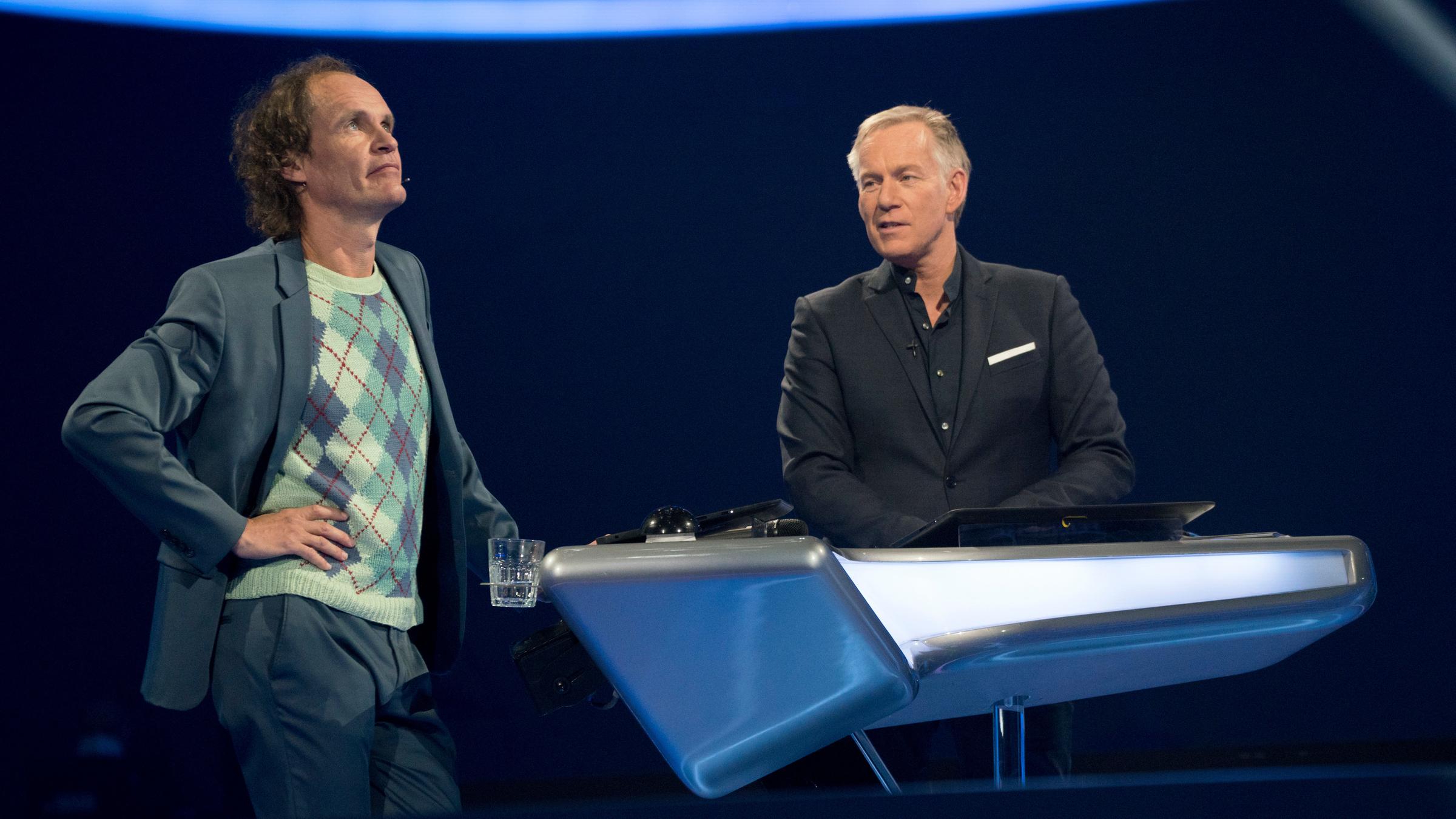 "Der Quiz-Champion - Das Promi-Special": Olaf Schubert und Johannes B. Kerner stehen am Ratepult. Olaf Schubert schaut fragend nach oben.