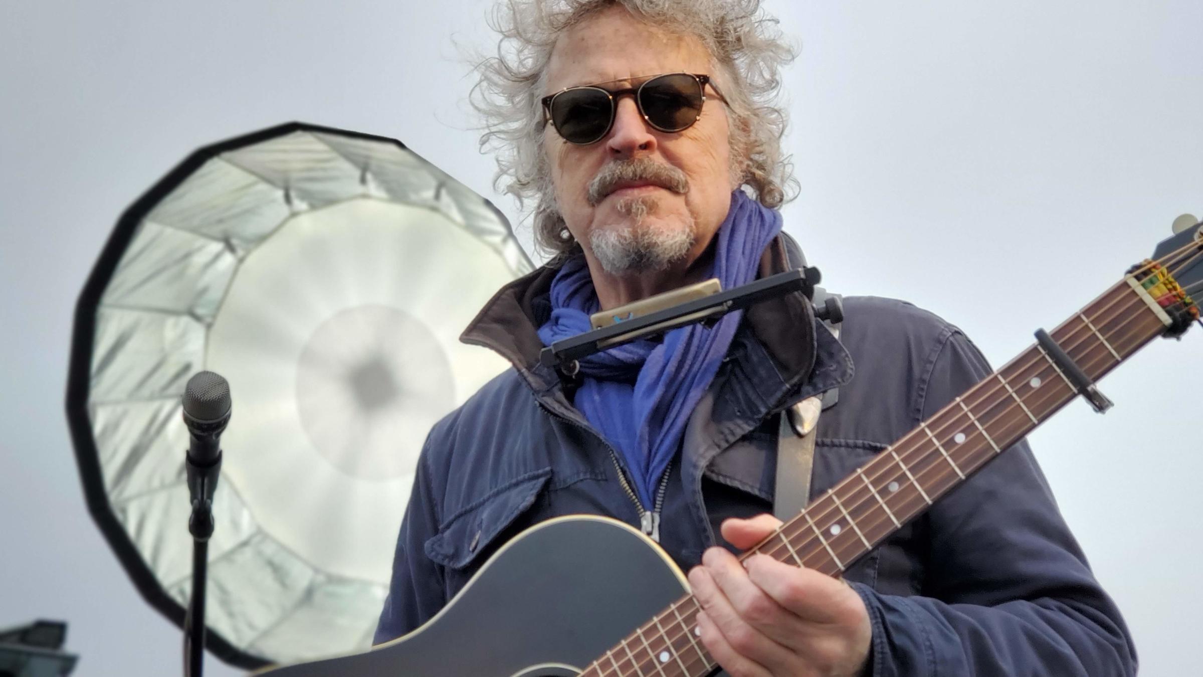 "Alles ist im Fluss - Wolfgang Niedecken zum 70.": Nahaufnahme von Wolfgang Niedecken mit Gitarre in der Hand. Im Hintergrund ein Aufheller.