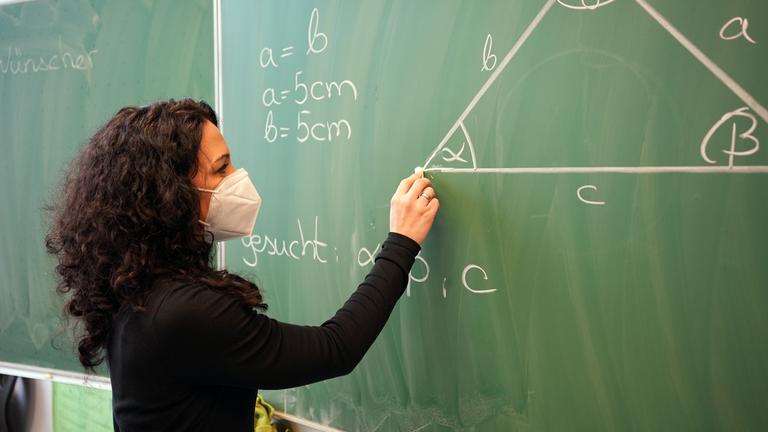 "WISO-Dokumentation: Schulen im Corona-Stress - Zwischen Schulheft und Tablet": Annika Wünschet unterrichtet mit Maske und schreibt etwas an die Tafel.