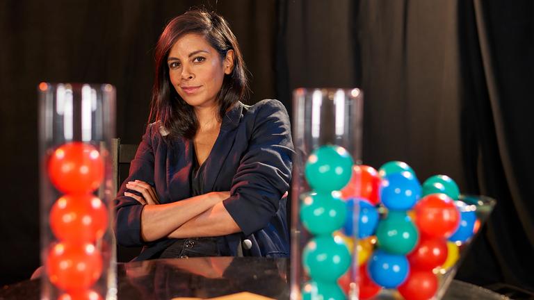 "Rabenmütter oder Super Moms? (2)": Die Moderatorin Collien Ulmen-Fernandes steht mit verschränkten Armen vor einen Stehtisch. Auf dem Tisch befinden sich Behälter, in denen bunte Bälle sind.