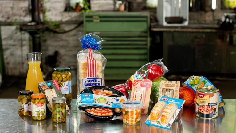 "ZDFzeit: Die Tricks der Lebensmittelindustrie - Sandwich, falscher Döner, Zwiebelringe": Zahlreiche Fertiggerichte auf einem Tisch.