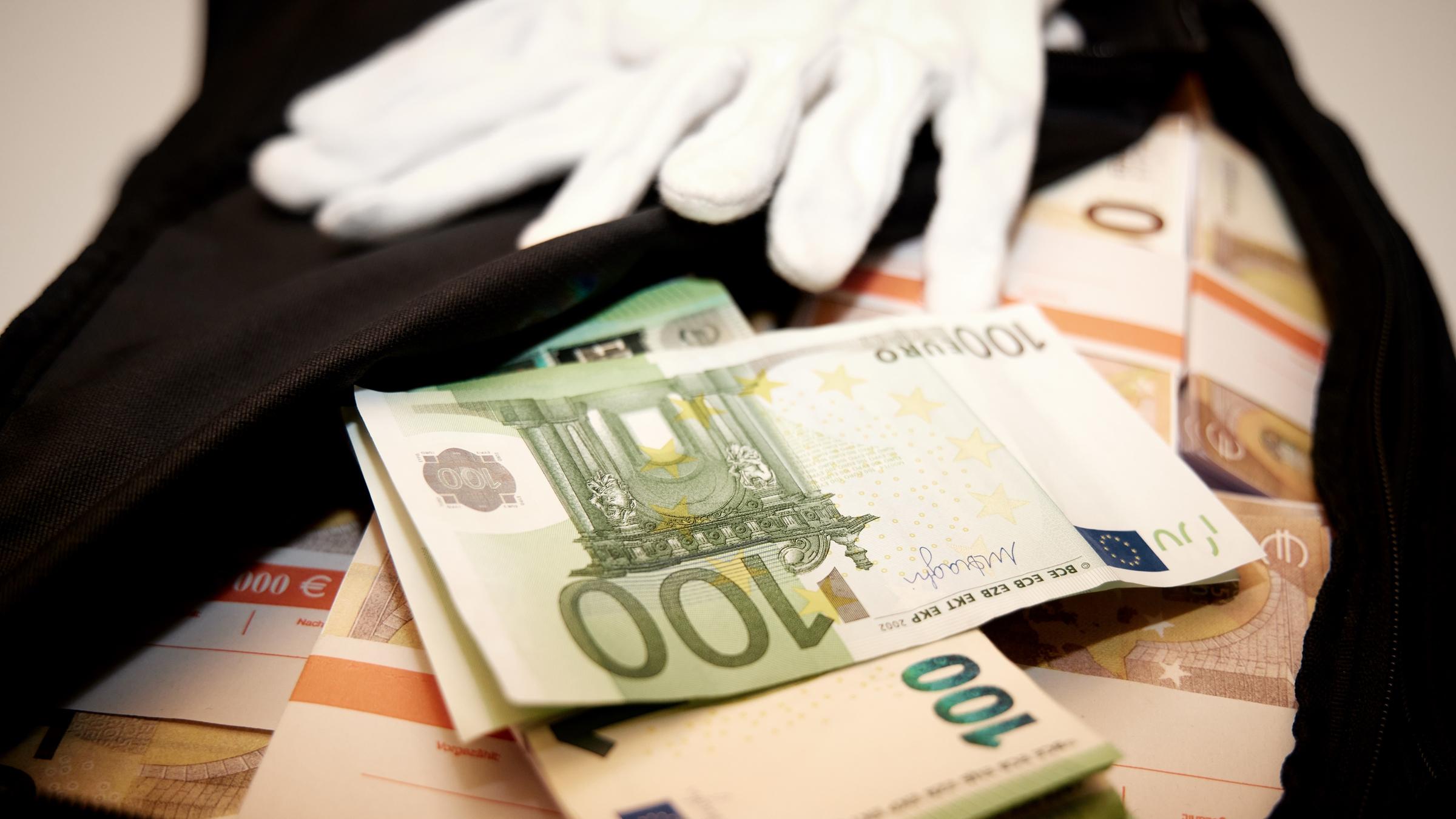 "ZDFzoom: Geldwäsche-Paradies Deutschland": In einer geöffneten schwarzen Tasche liegen Bündel von 100- und 50-Euro-Scheinen. Auf der Tasche liegt ein Paar weiße Handschuhe.