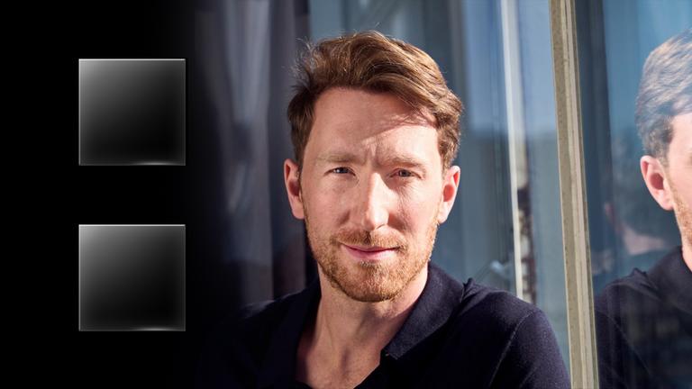 "ZDFzeit: Die Wahrheit übers Erben - Warum Reiche immer reicher werden": Louis Klamroth schaut in die Kamera, sein Kopf spiegelt sich in einem Fenster.