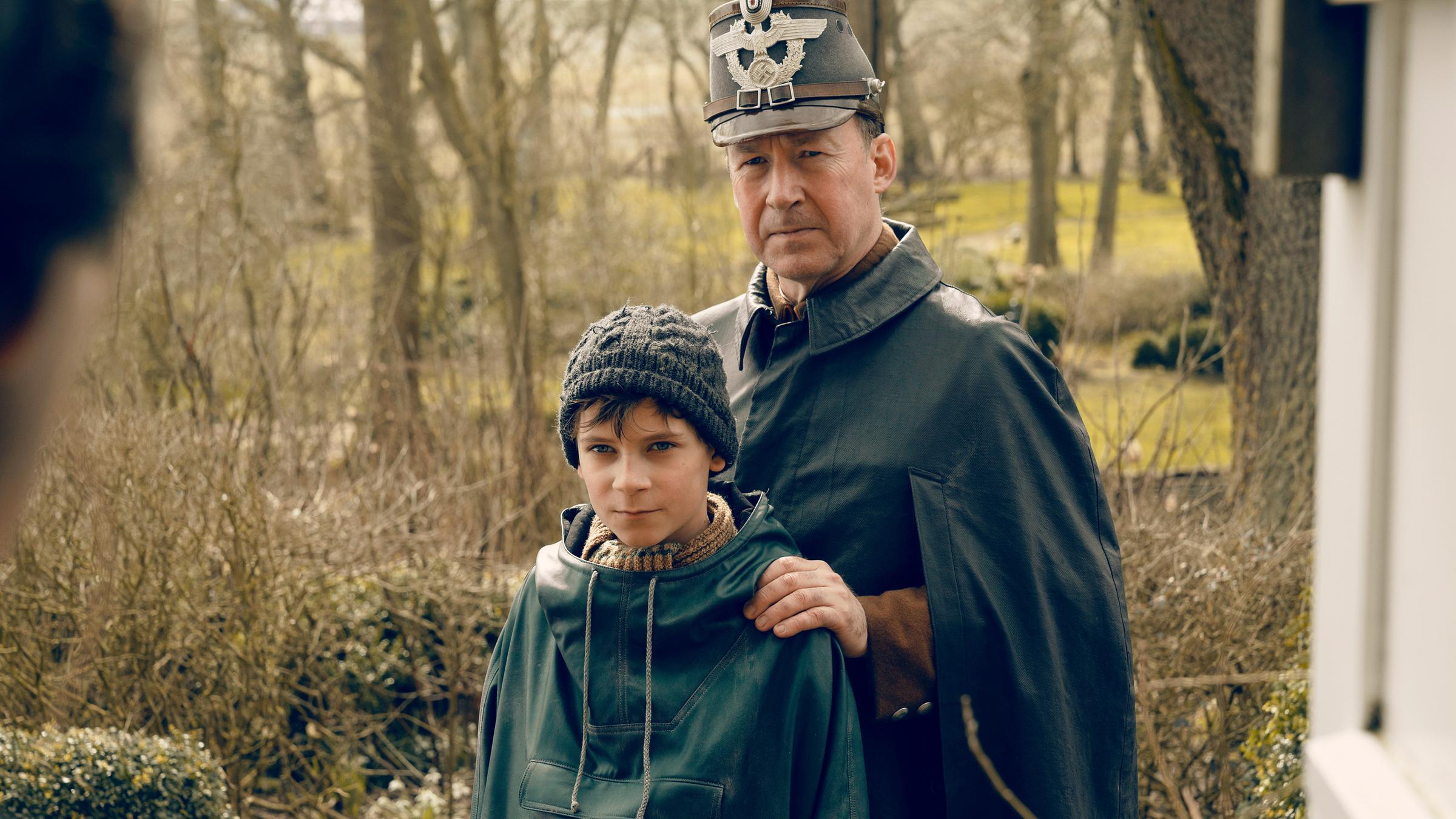 "Deutschstunde": Jens Ole Jepsen (Ulrich Noethen) und Siggi Jepsen (Levi Eisenblätter) stehen nebeneinander und schauen in die Kamera. Jens Ole hat seine Hände auf die Schultern seines Sohnes gelegt.