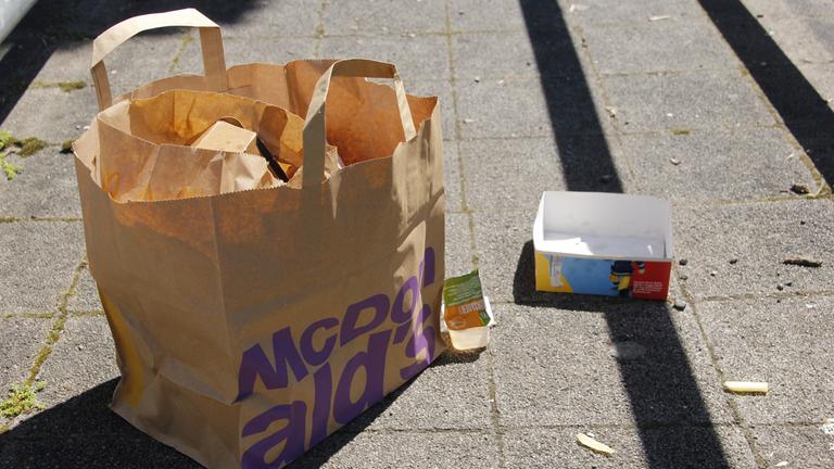 "planet e.: Fast Food - Das große Fressen": Müll nach dem Verzehr von Fast Food, der auf einer Straße liegt.