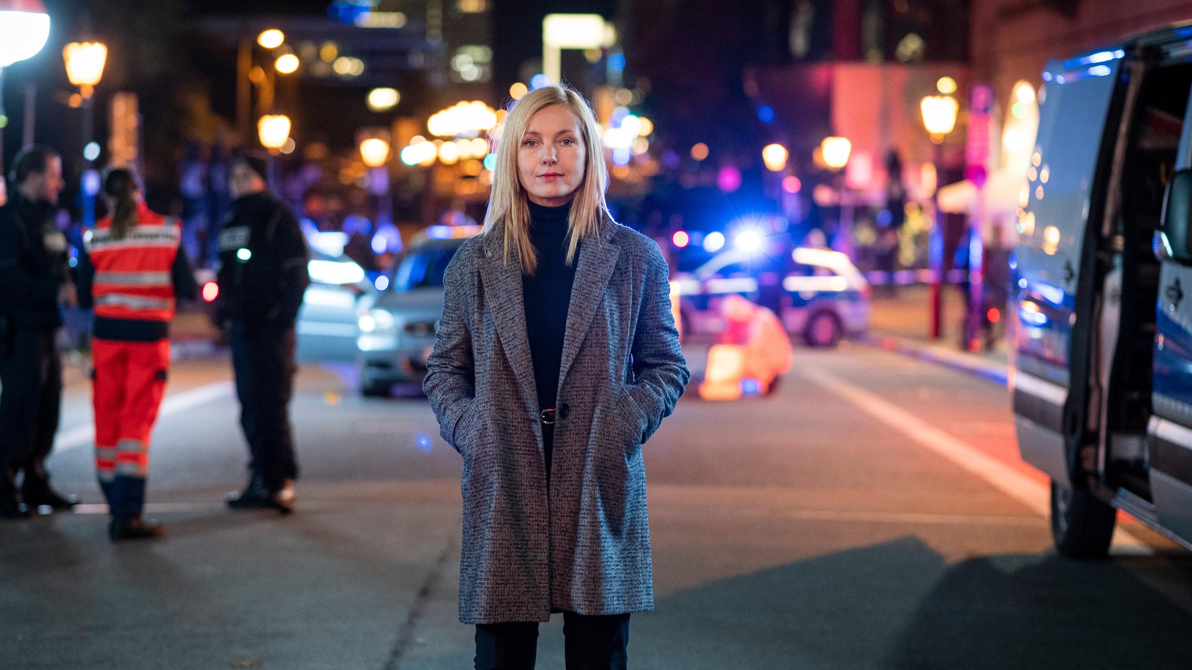 "Die Jägerin - Nach eigenem Gesetz": In einer nächtlichen Berliner Straßenszene steht Judith Schrader (Nadja Uhl) zentral im Bild und blickt frontal in die Kamera. Polizisten agieren im Hintergrund.