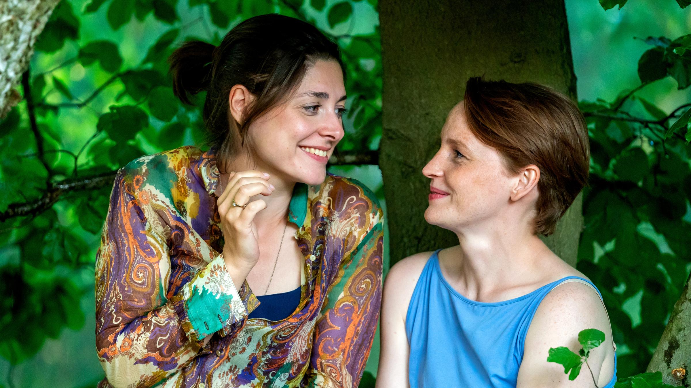 "WIR - Gewitter": Helena (Katharina Nesytowa, links) und Annika (Eva Maria Jost, rechts) sitzen in ihrem Baumhaus und schauen sich lächelnd an.