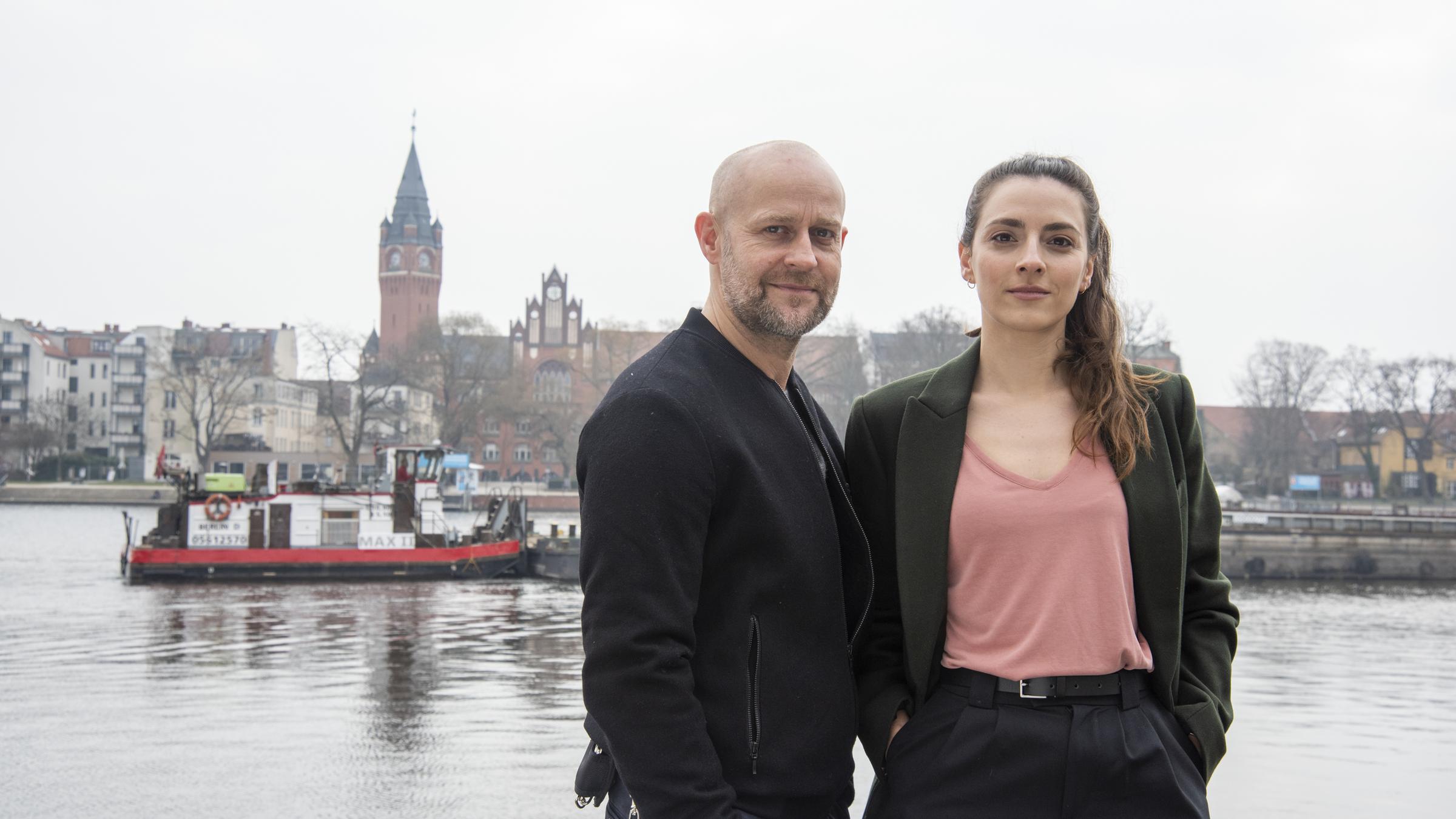"Jenseits der Spree - Blutsbande": Rober Heffler (Jürgen Vogel) und Kay Freund (Seyneb Saleh) stehen tagsüber an der Spree. Auf dem Fluss sind Boote. Auf der anderen Seite ist das Rathaus von Köpenick zu sehen.