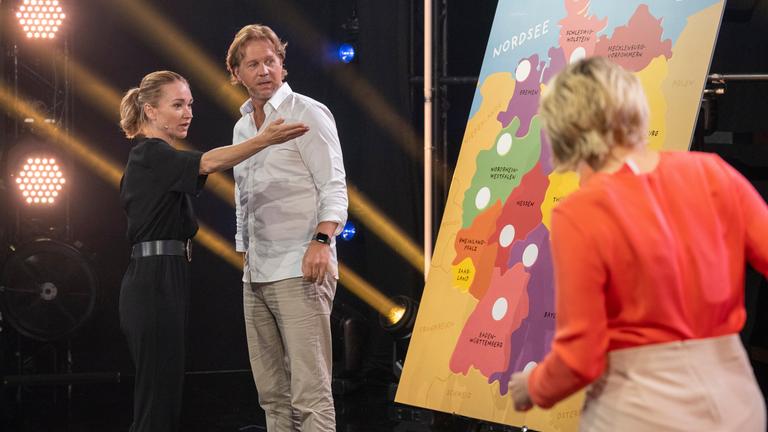 "Das große Deutschland-Quiz": Lisa Maria Potthoff und Thomas Heinze stehen an einer Deutschlandkarte. Sabine Heinrich ist von hinten zu sehen. Sie steht auf der anderen Seite an der Deutschlandkarte.