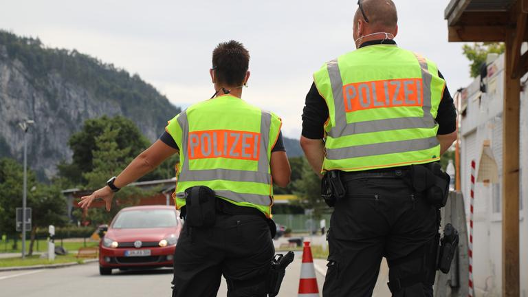 "ZDF.reportage: Dürfen die das - Coronaregeln und kein Ende": Zwei Polizeibeamten mit gelber Warnweste an einem Grenzübergang.