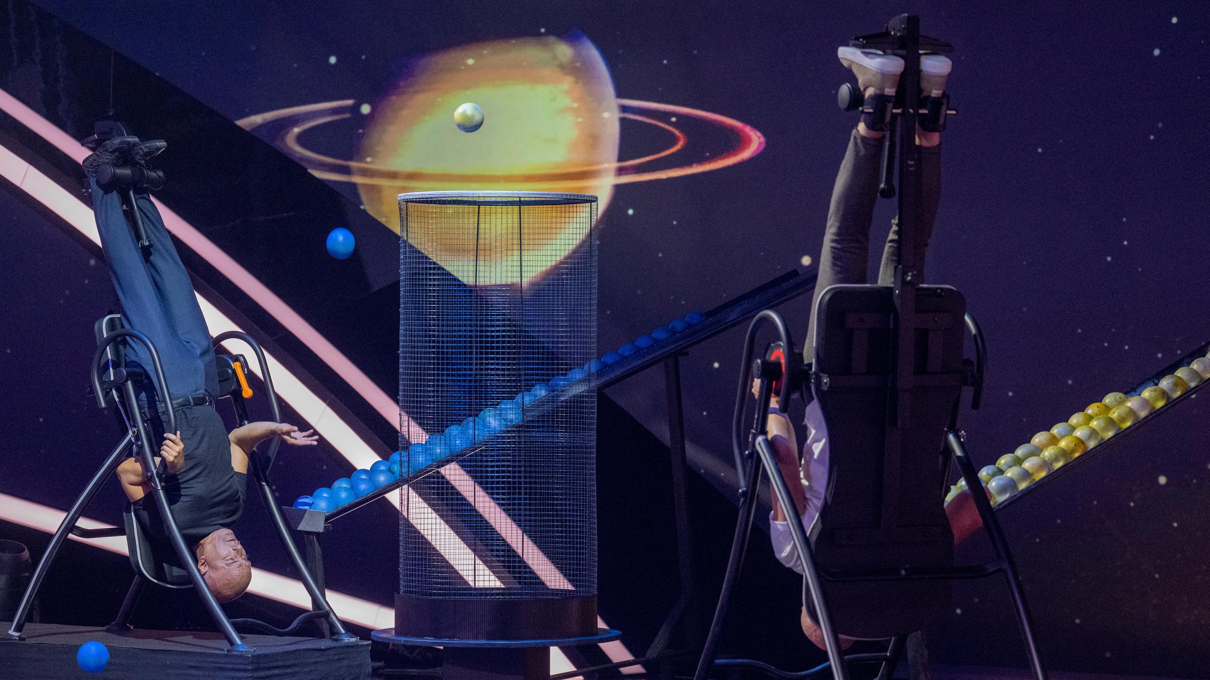 "Die große "Terra X"-Show - Kräfte der Natur": Christoph Maria Herbst und Devid Striesow sind während eines Ballspiels mithilfe eines Sportgerätes auf den Kopf gestellt.