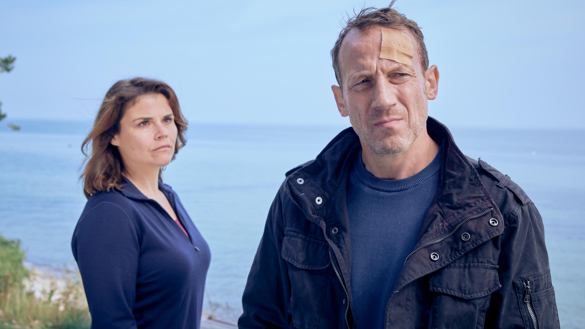 "Stralsund - Die rote Linie": Nina Petersen (Katharina Wackernagel) steht hinter Benjamin Lietz (Wotan Wilke Möhring) auf einer Terrasse am Meer.