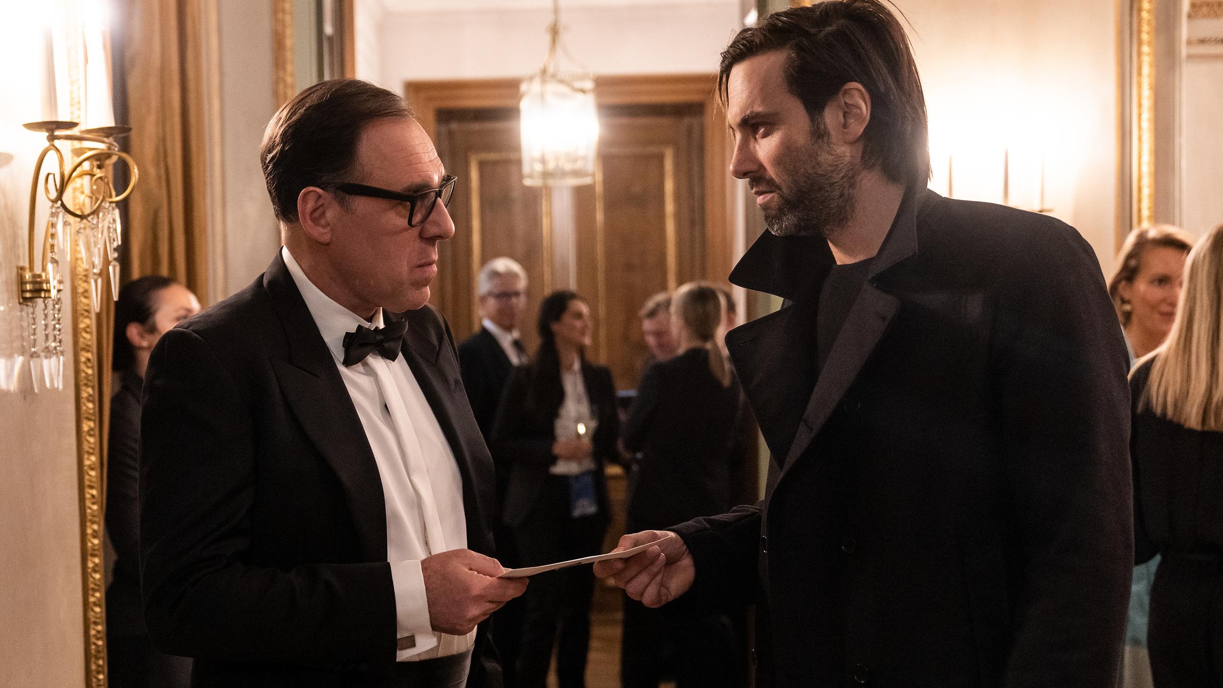 "Laim und das Hasenherz": Lukas Laim (Max Simonischek) übergibt Maximilian Kronberger (Thomas Loibl) einen Umschlag.