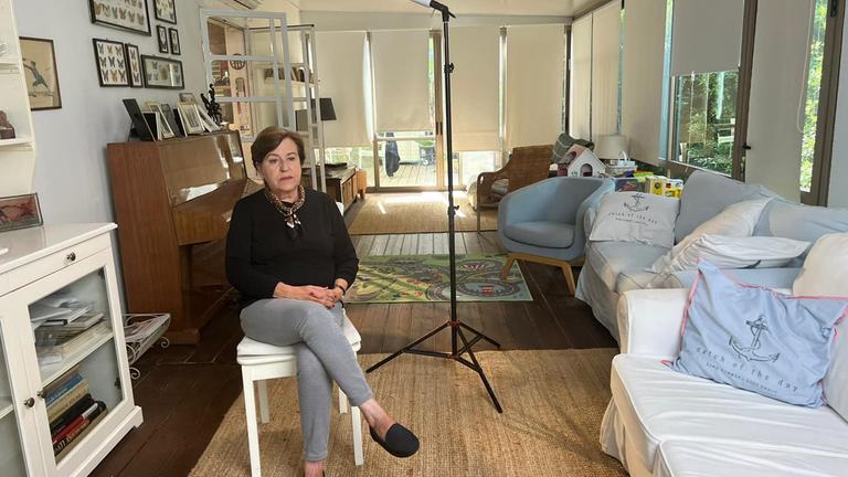 "München '72 - Anschlag auf Olympia. Heitere Spiele, tödlicher Terror": Ankie Spitzer, deren Ehemann André von Terroristen beim Olympia-Attentat getötet wurde, wird gerade für ein Interview vorbereitet. Sie sitzt auf einem Stuhl im Wohnzimmer ihres Hauses. Neben ihr steht ein Scheinwerfer. Sie trägt einen schwarzen Pullover und eine graue Hose.