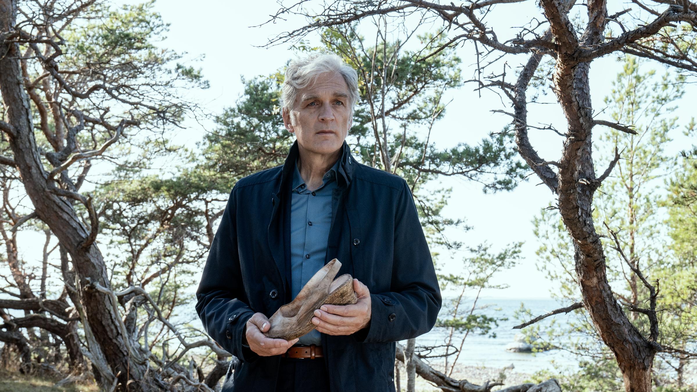 "Der Kommissar und das Meer - Woher wir kommen - wohin wir gehen": Robert Anders (Walter Sittler) hält einen schmutzigen Damenschuh in der Hand und blickt nachdenklich ins Leere.