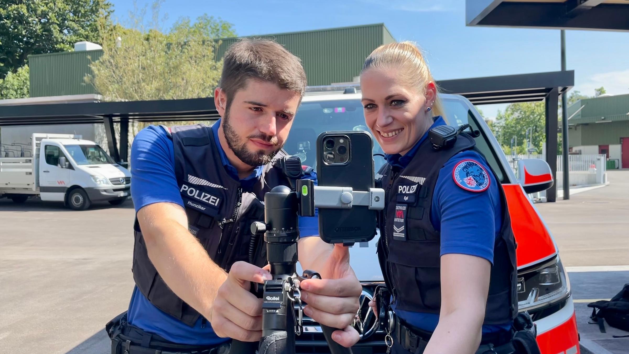 "Influencer in Uniform - Polizei und Social Media": Eine Polizistin und ein Polizist schauen sich ihre gedrehten Filmaufnahmen auf einem Handy an.