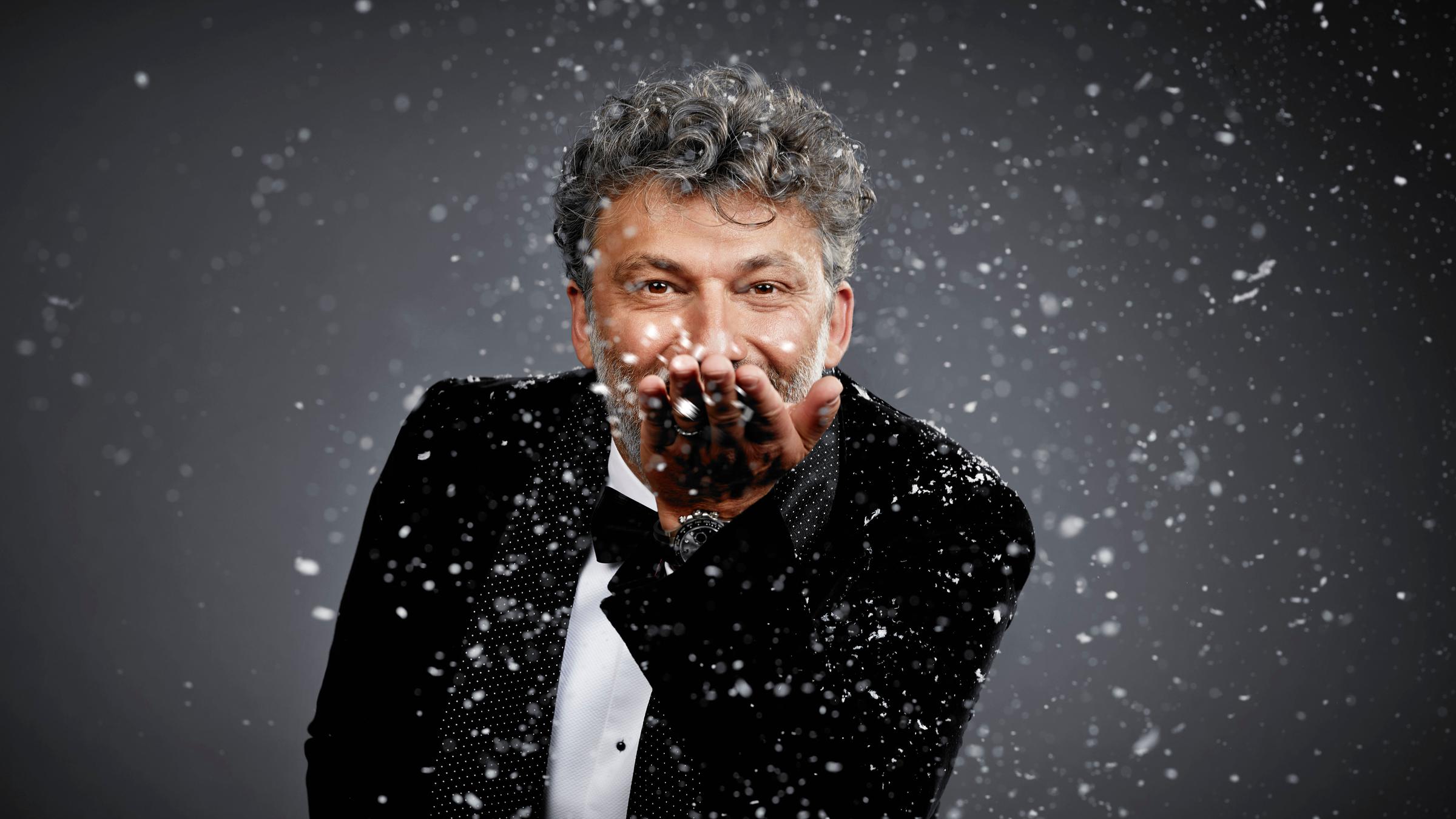 "Weihnachten im Erzgebirge mit Jonas Kaufmann": Jonas Kaufmann blickt lächelnd in die Kamera und bläst Kunstschnee in die Luft.