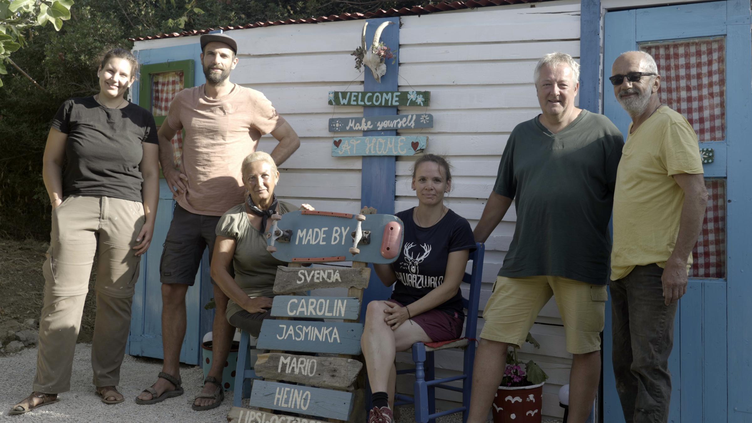 "Offline - zurück zur Besinnung": Sechs Männer und Frauen stehen vor einem weiß-blauen Holzhäuschen. In ihrer Mitte stehen ihre Namen auf Schilder geschrieben.