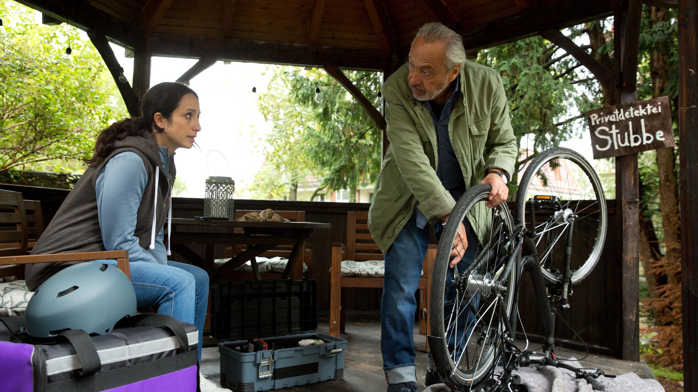 "Stubbe - Ausgeliefert": Christiane (Stephanie Stumph) sitzt vor Stubbe (Wolfgang Stumph), der ein umgedrehtes Fahrrad repariert. Die beiden schauen sich an.