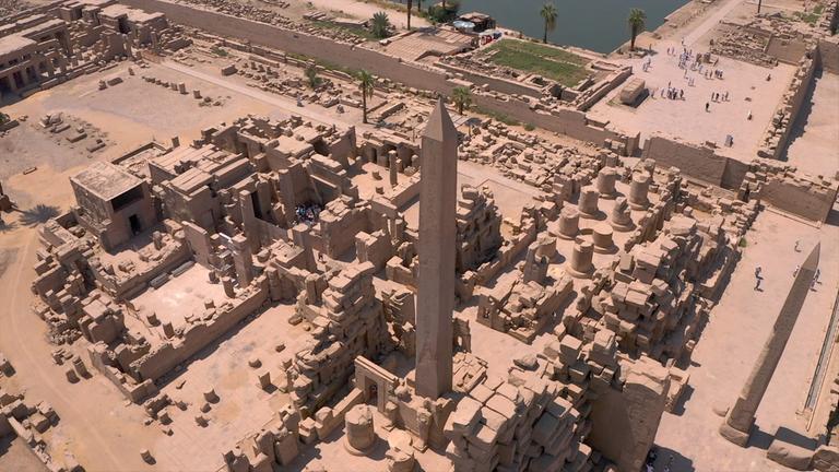 "Terra X: Ungelöste Fälle der Archäologie - Technik": Luftaufnahme des altägyptischen Tempels von Karnak, von dem diverse Bauten, ein kleiner Teil eines künstlichen Sees, sowie ein großer Obelisk zu sehen sind.