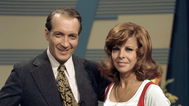 "Erkennen Sie die Melodie?: Ernst Stankowski und  Assistentin Monika Strauch stehen nebeneinander im Studio und lächeln in die Kamera