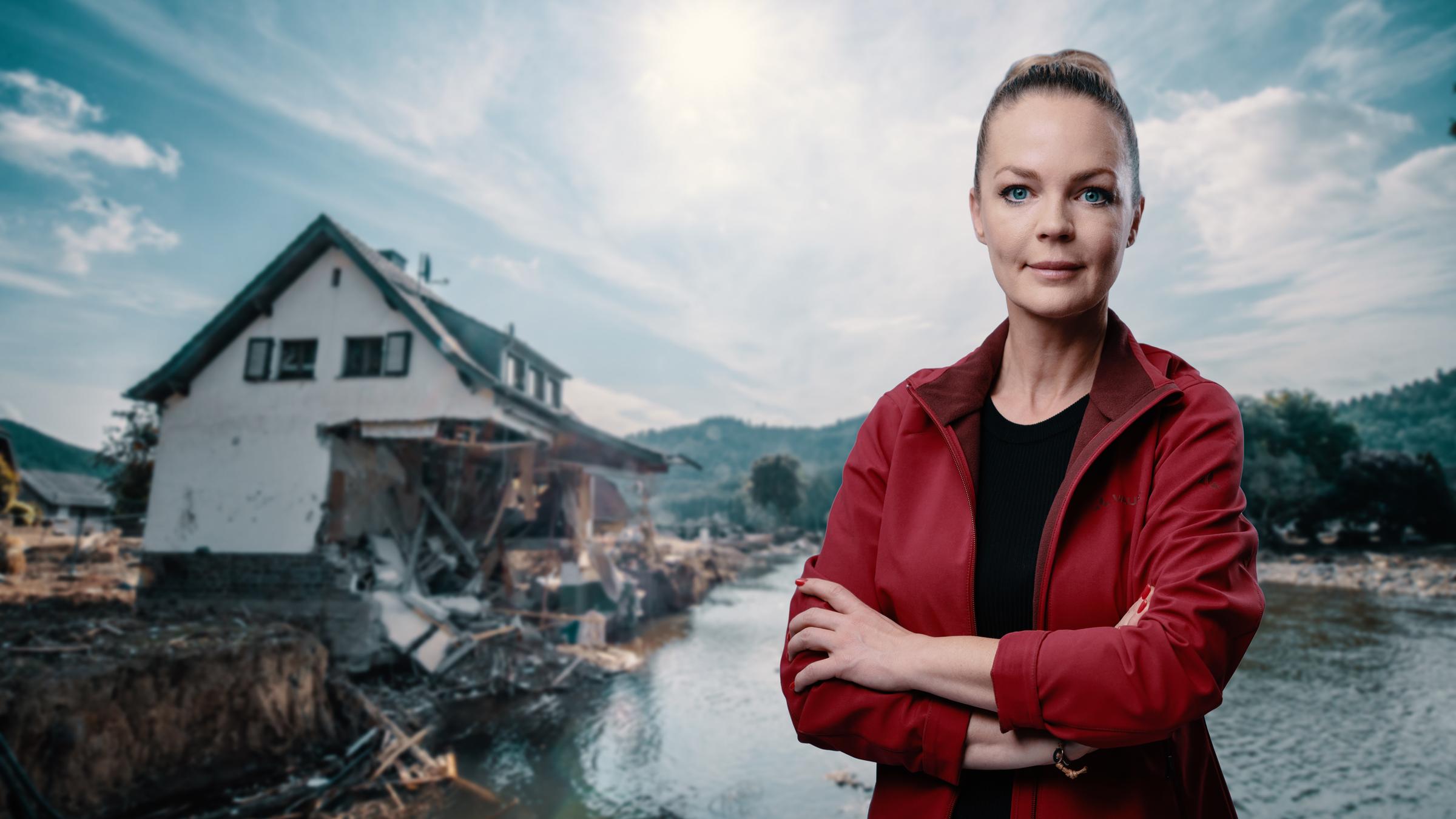"ZDFzeit: Nach der Flut - Eva Brenner hilft an der Ahr": Vor dem Hintergrund eines zerstörten Hauses steht in der rechten Bildhälfte mit verschränkten Armen Eva Brenner in roter Outdoorjacke.