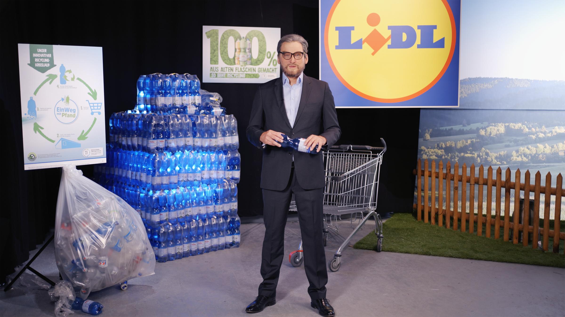 "ZDFzeit: Lidl: Die Insider - Verkaufstricks beim Discounter-Riesen": Verkleideter Insider steht vor Wasserflaschen und dem Lidl-Logo.