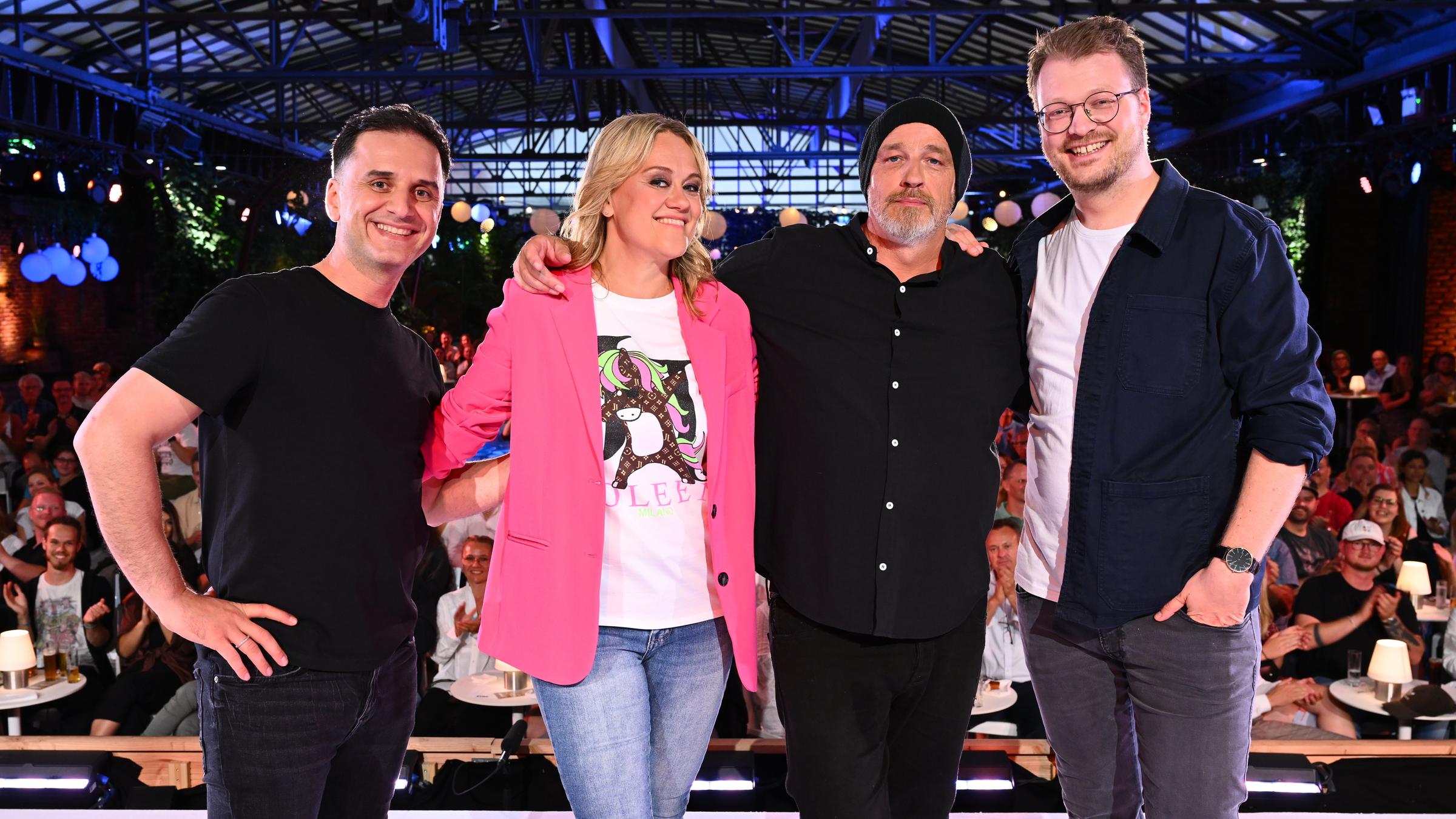 "Der ZDF Comedy Sommer": Die vier Künstler des Abends Özcan Cosar, Lisa Feller, Torsten Sträter, Maxi Gstettenbauer stehen mit dem Rücken zum Publikum und lächeln in die Kamera.