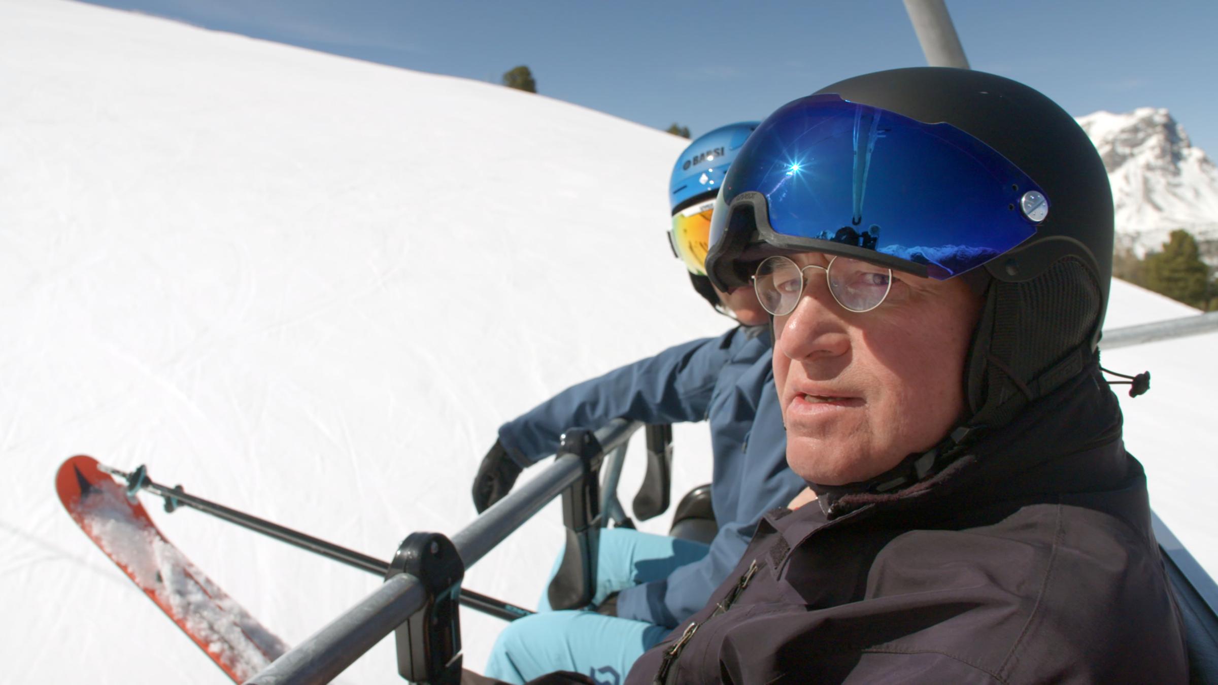 "ZDFzeit: Mensch Gysi! Grenzgänger zwischen Ost und West": Gregor Gysi mit Skihelm in einem Skilift vor winterlicher Landschaft.