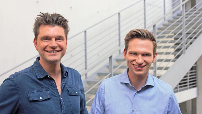 "heute-show spezial": Lutz van der Horst und Fabian Köster stehen lächelnd im Treppenhaus im Deutschen Bundestag und freuen sich auf die neue Spezial-Ausgabe. Im Hintergrund ist Stahltreppe zu sehen.