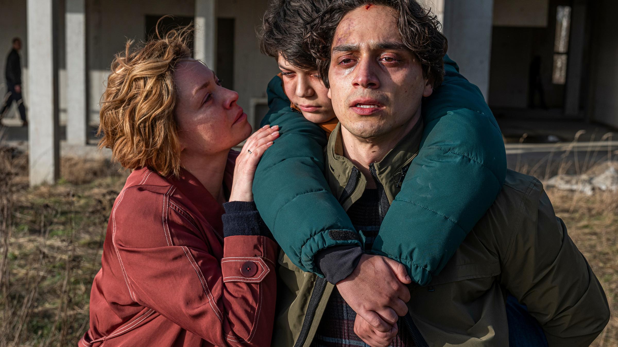 "Dr Überfall": Miriam (Karolina Lodyga) und Damon (Yasin Boynuince) haben den kleinen Arian (Elias Danesh Hartmann) endlich befreien können. Damon trägt Arian auf dem Rücken. Miriam schaut Arian an und hat ihre rechte Hand auf seine Schulter helegt. Alle drei schauen erschöpft und entsetzt.