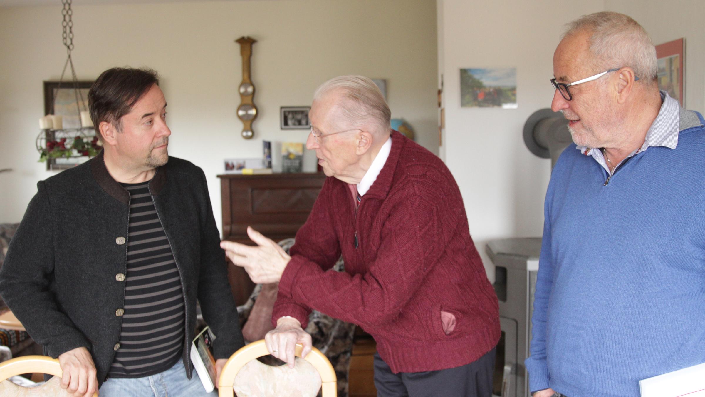 "Honecker und der Pastor - Die Dokumentation". Jan Josef Liefers und Fred Breinersdorfer stehen im Wohnzimmer von Uwe Holmer.