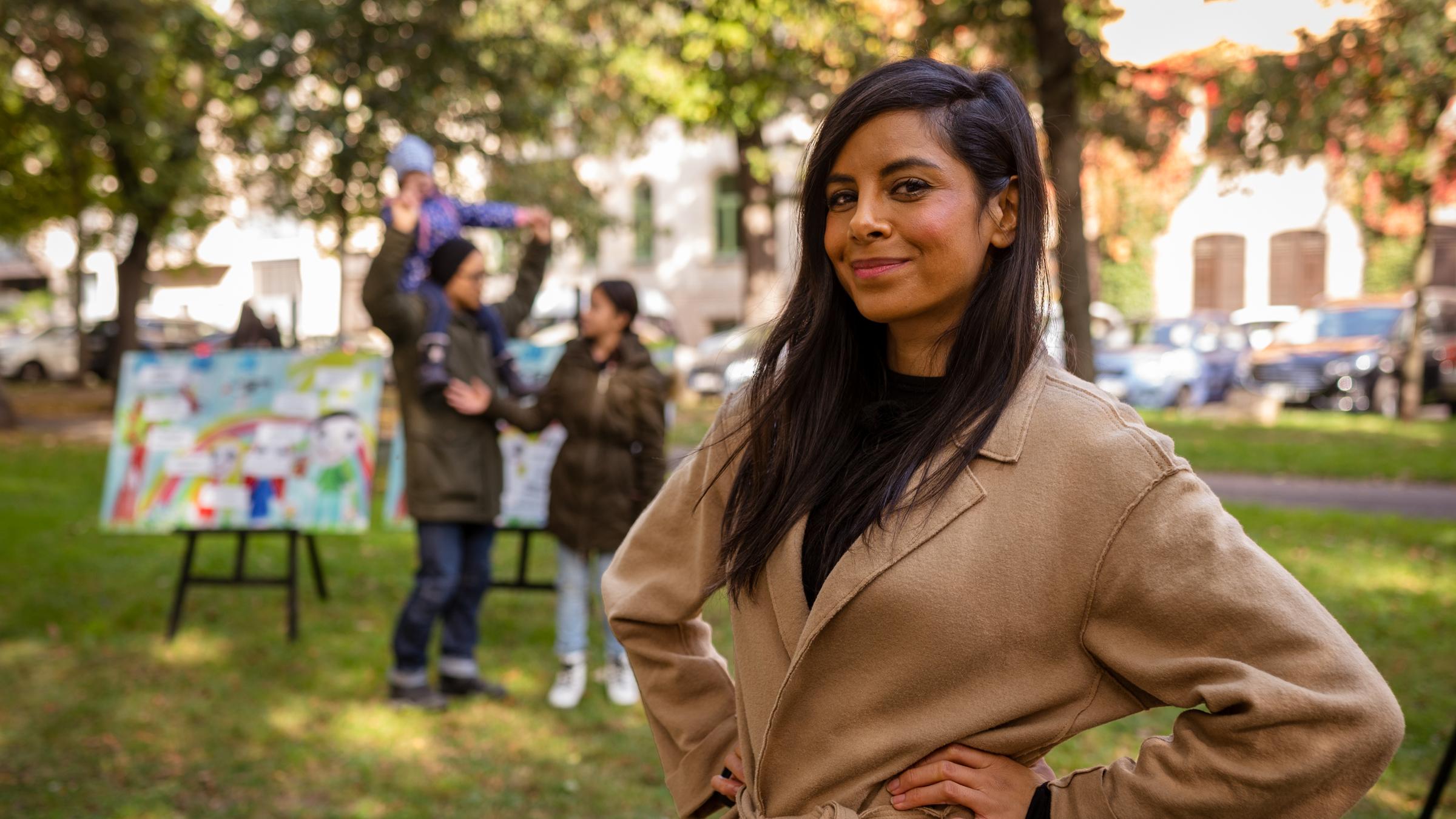 "Rabenväter oder Super Dads? (1)": Moderatorin Collien Ulmen-Fernandes im Park. Im Hintergrund steht ein Vater mit seiner Tochter.