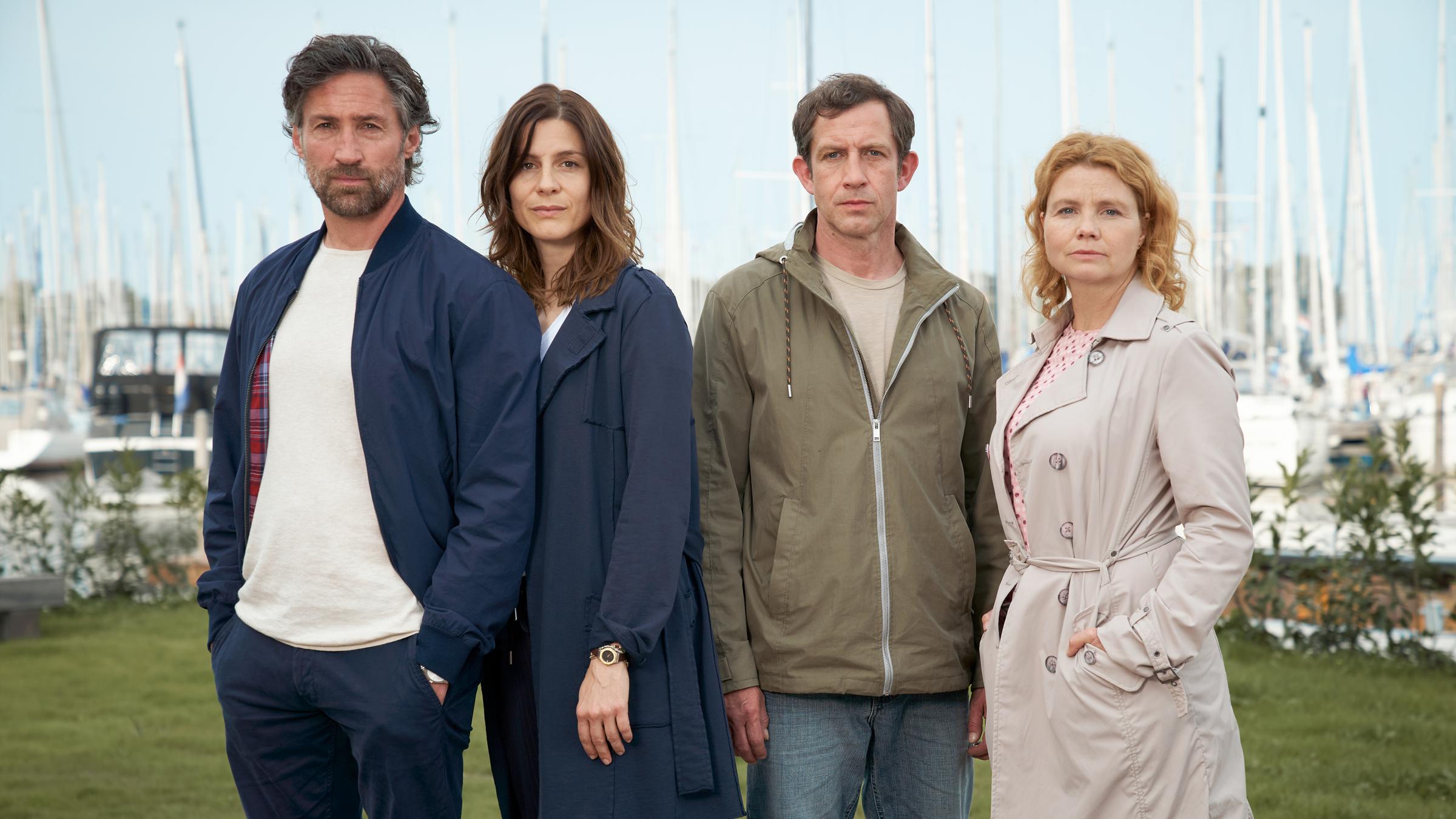 "Leben über Kreuz": Sebastian Blumberg (Benjamin Sadler), Caren Blumberg (Christina Hecke), Jan Kempe (André Szymanski) und Birthe Kempe (Annette Frierm) stehen dicht beieinander und im Hintergrund erkennt man mehrere Segelboote.