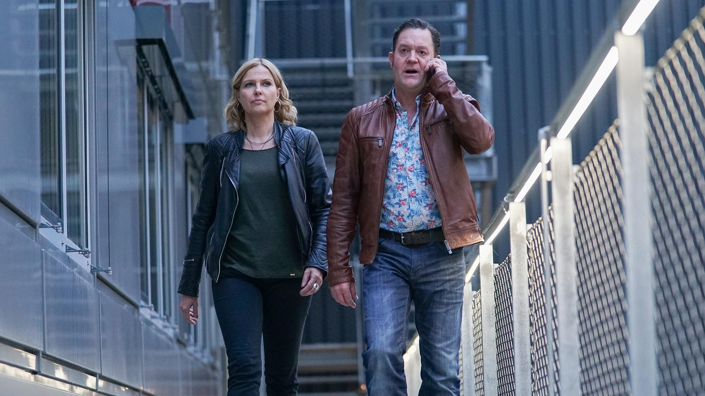 "Die Chefin – Glück": Vera Lanz (Katharina Böhm) und der telefonierende Paul Böhmer (Jürgen Tonkel) gehen nebeneinander an einem Gebäude entlang.