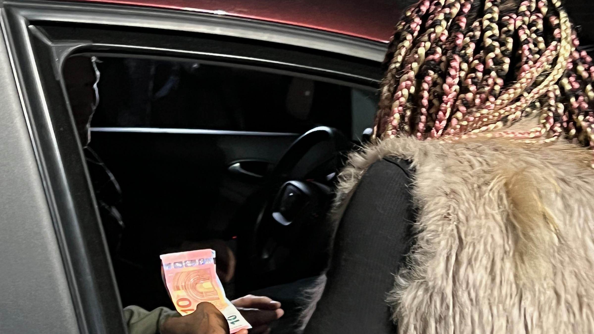 "Billigware Sex - Ausgebeutet für 30 Euro": Junge Frau erhält Geld von Person in Auto.