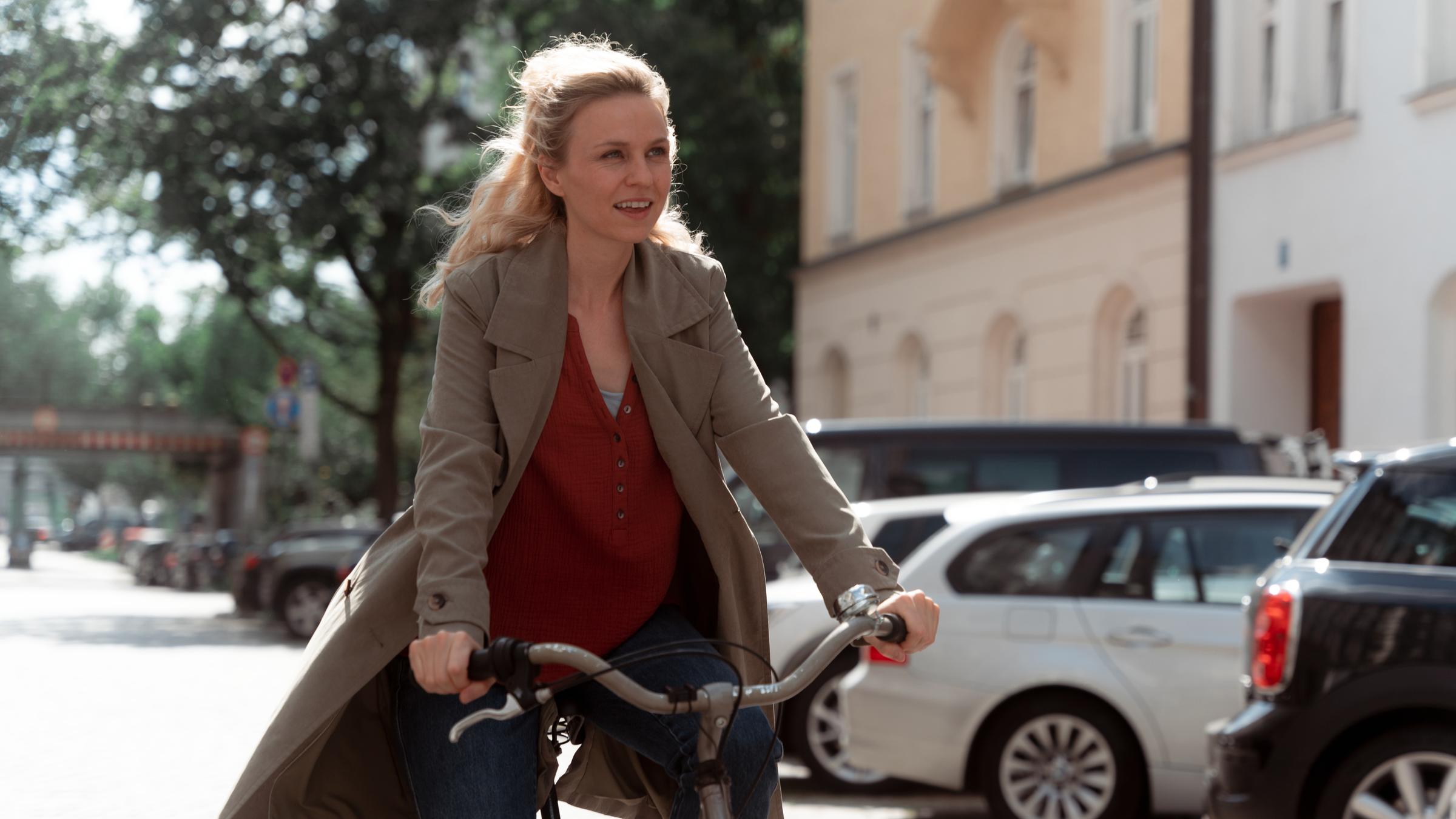 "Wer füttert den Hasen?": Jule Meisner (Teresa Rizos) fährt mit einem glücklichen Gesichtsausdruck auf ihrem Fahrrad durch die Straße.