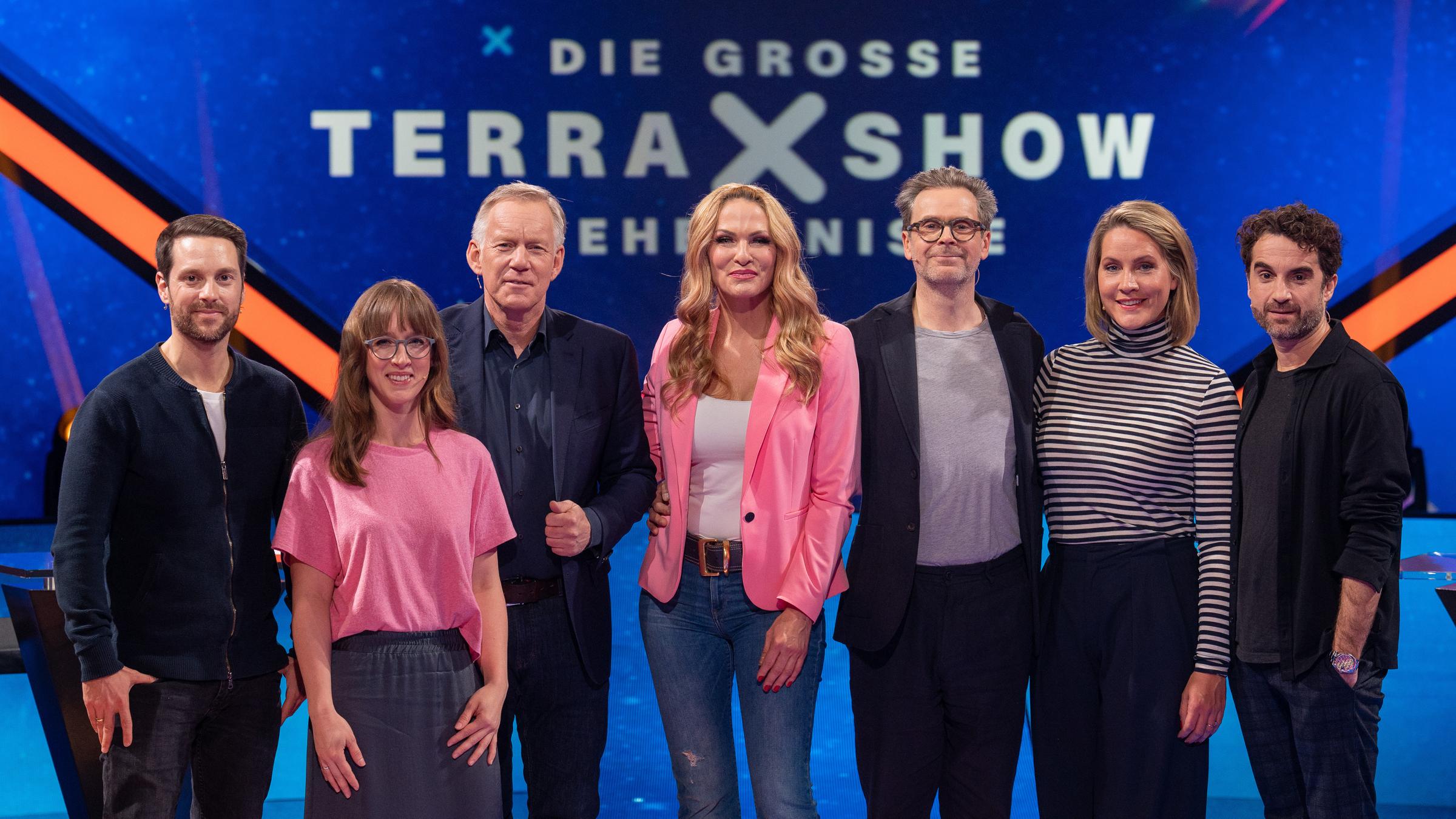 "Die Terra X-Show - Geheimnisse": Mirko Drotschmann, Insa Thiele-Eich, Johannes B. Kerner, Sonya Kraus, Matthias Matschke, Judith Rakers und Oliver Wnuk stehen im Studio vor dem Sendungslogo und lachen in die Kamera.