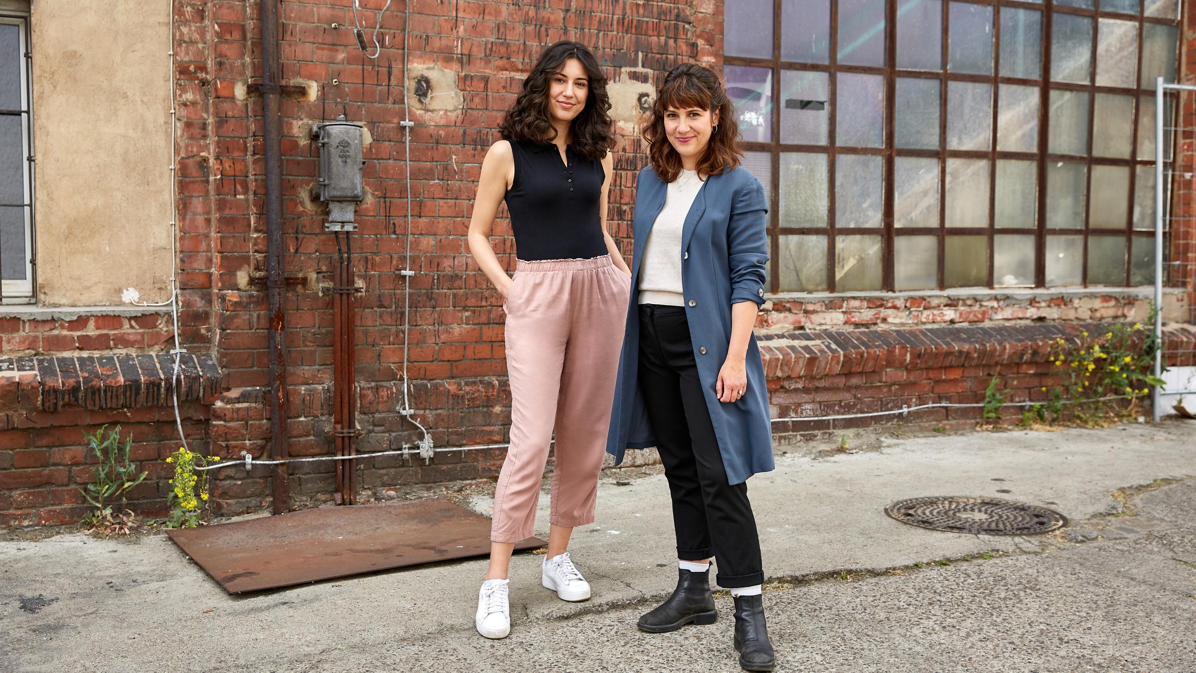 Die Hosts von "plan b: Da geht was, Deutschland!" Refiye Ellek  (l.) und Antonia Lilly Schanze (r.) stehen vor einer alten Fabrik.