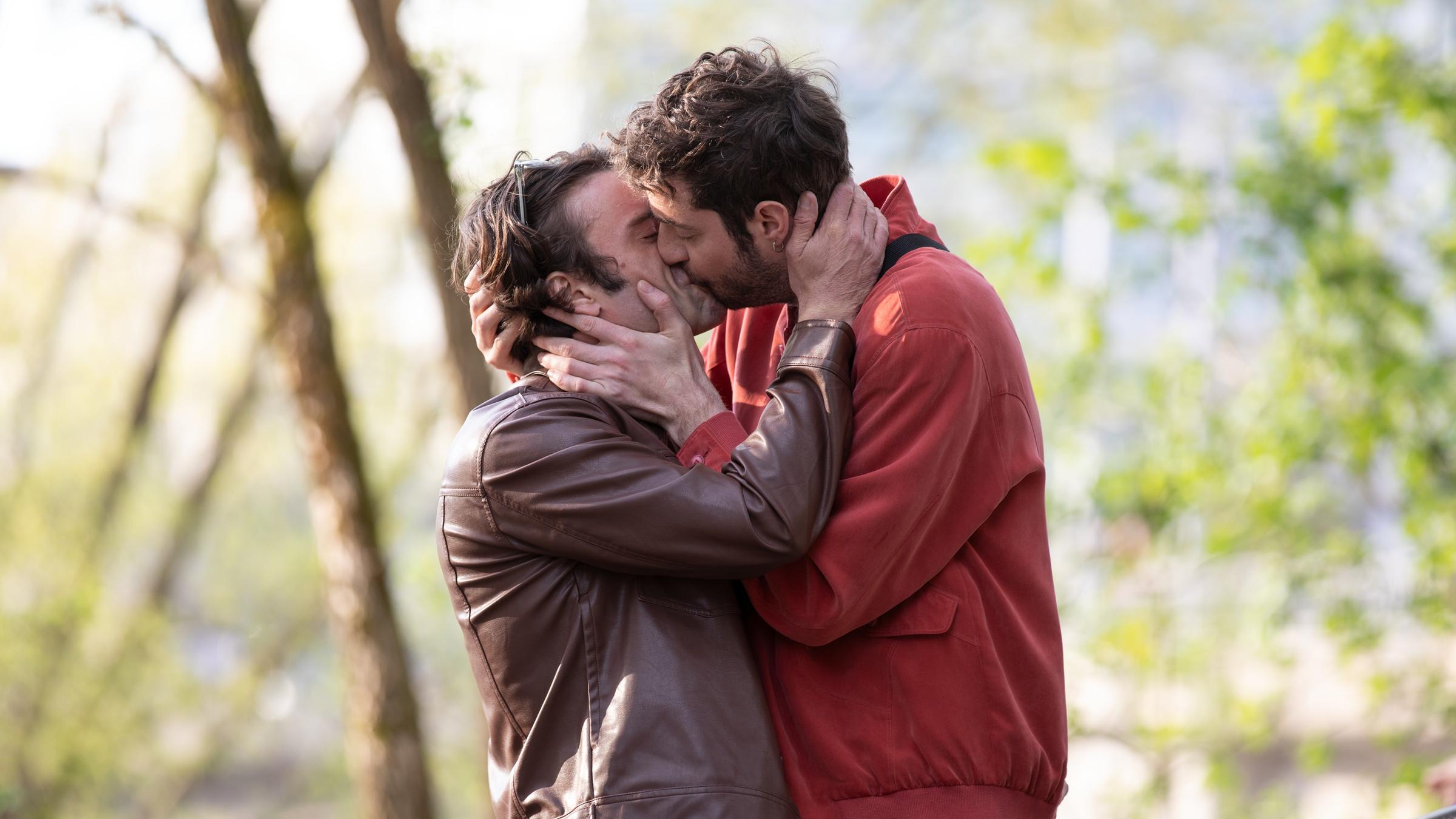 "Ready.Daddy.Go! - Babyblues": Michel (Fridolin Sandmeyer) und Dirk (Florian Jahr) stehen in einem Park und küssen sich eng umschlungen und leidenschaftlich.