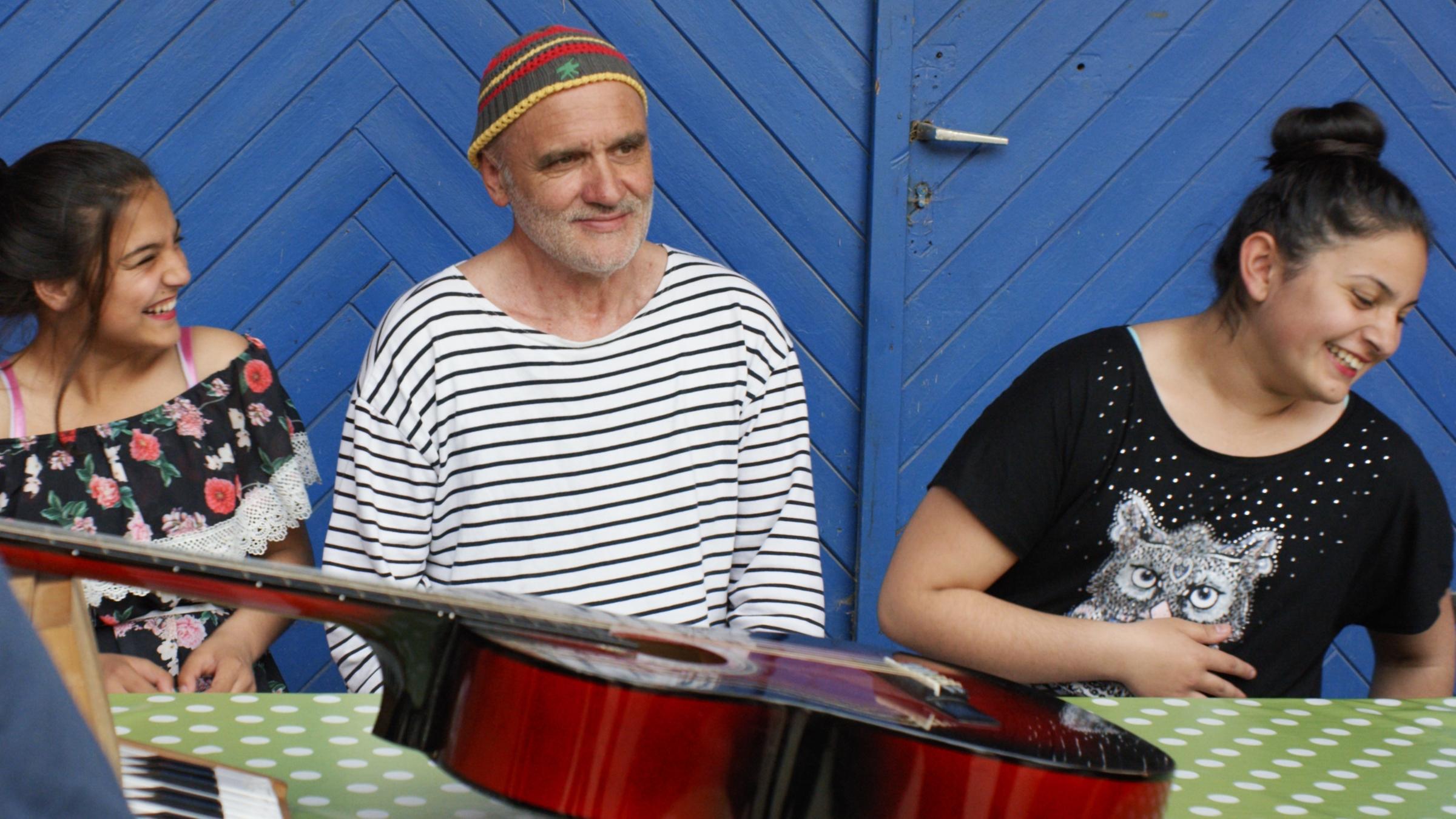 "Herr Bachmann und seine Klasse": Ein Mann mit Bart sitzt zwischen zwei Mädchen.