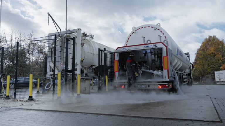 "ZDFzoom: LNG: Zu viel, zu teuer, schlecht fürs Klima - Ist der Flüssiggas-Boom ein Irrweg?": Mann in Arbeitsmontur steht vor aufgeklapptem hinteren Teil eines Tankwagens.